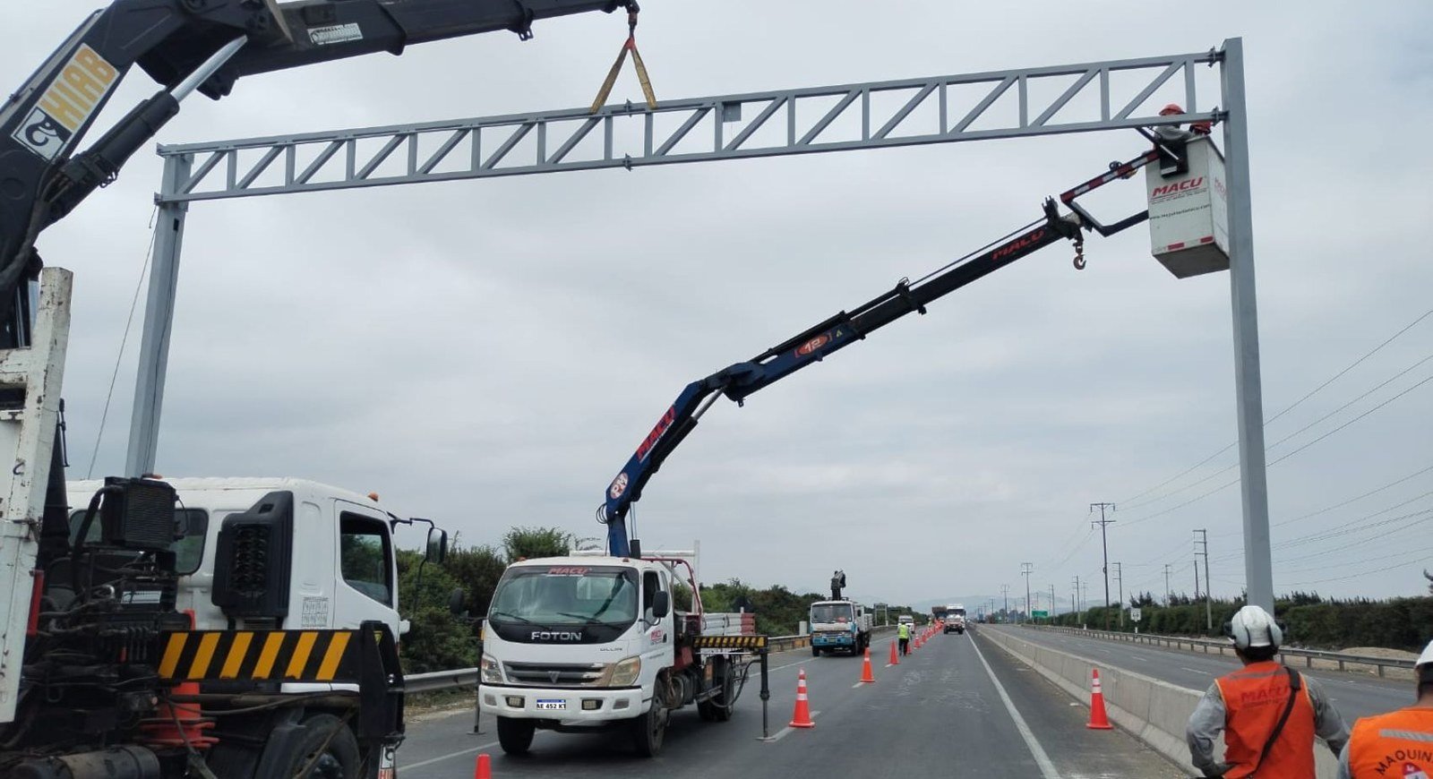 Camión grúa izando un poste con operarios