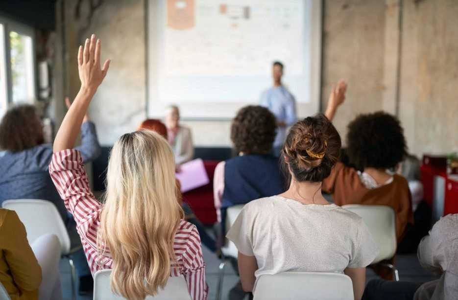 Participantes en una capacitación levantando la mano